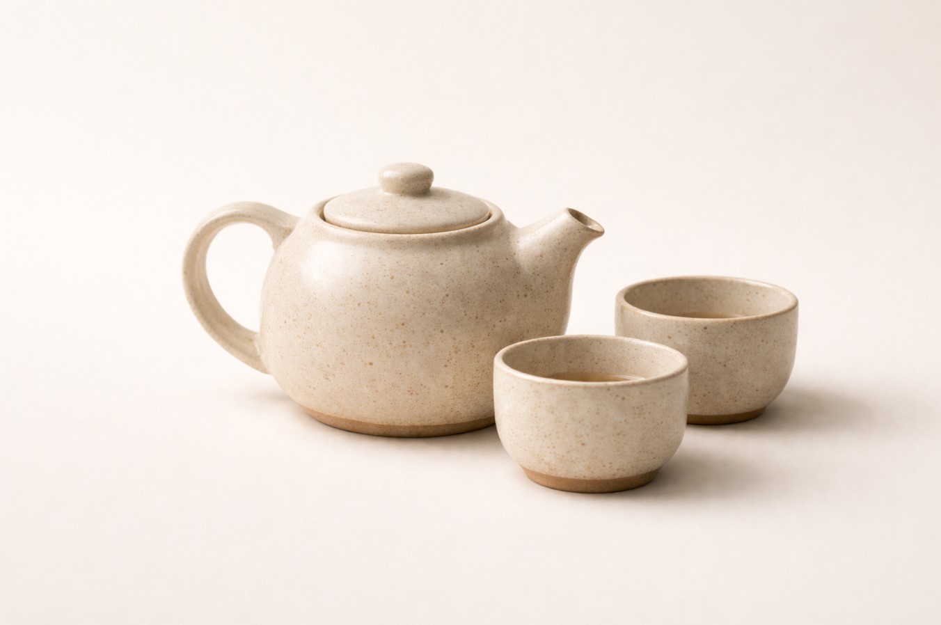 Studio packshot of handmade tea set: teapot with two cups on neutral background