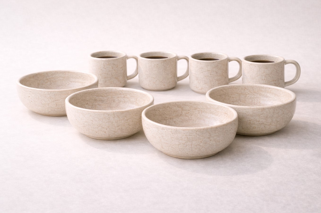 Studio packshot of ceramic breakfast set with bowls and mugs on neutral background